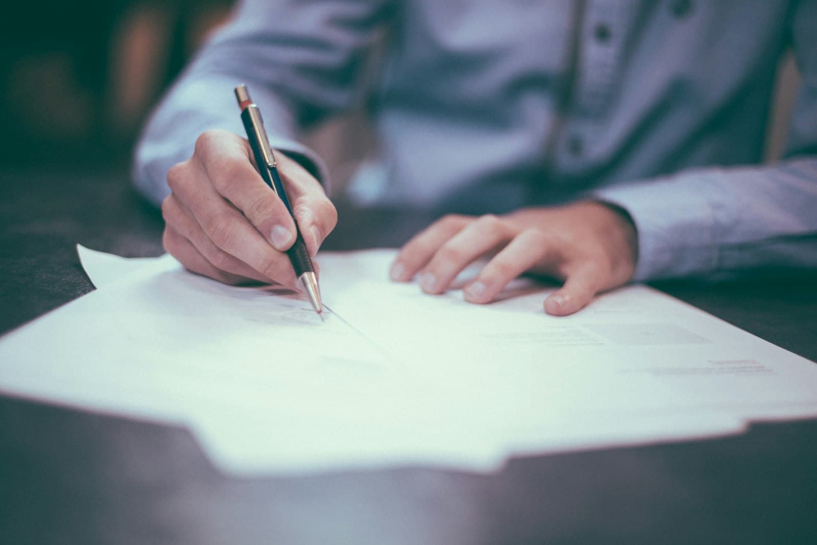 Hands signing documents at a bright table