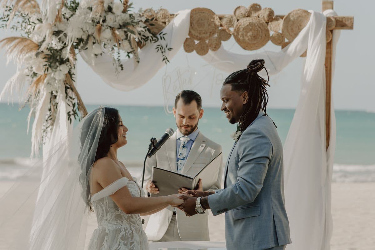 A couple holding hands during an outdoor beachside wedding ceremony
